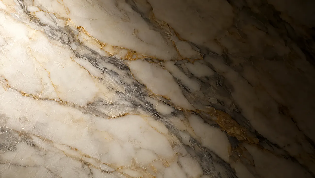 Macro view of honed Calacatta marble with grey and gold veining under raking light